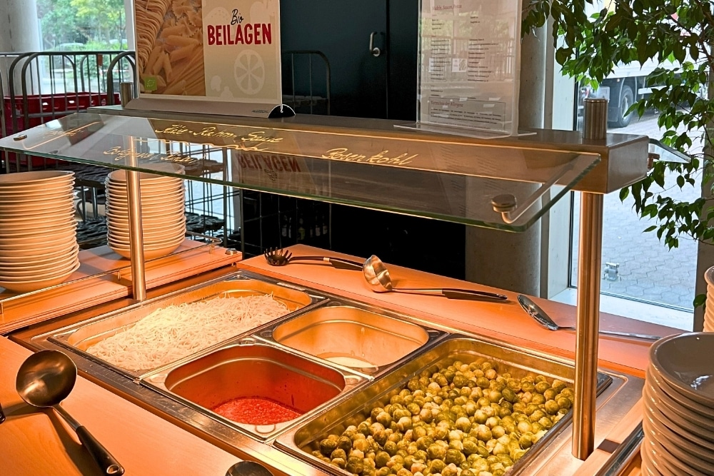 Rosenkohl, Nudeln und Sauce sind auf einem Buffet zur Selbstbedienung aufgebaut.